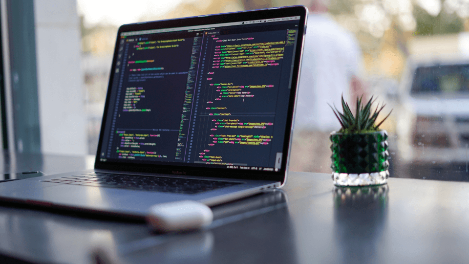 Laptop over table displaying HTML code